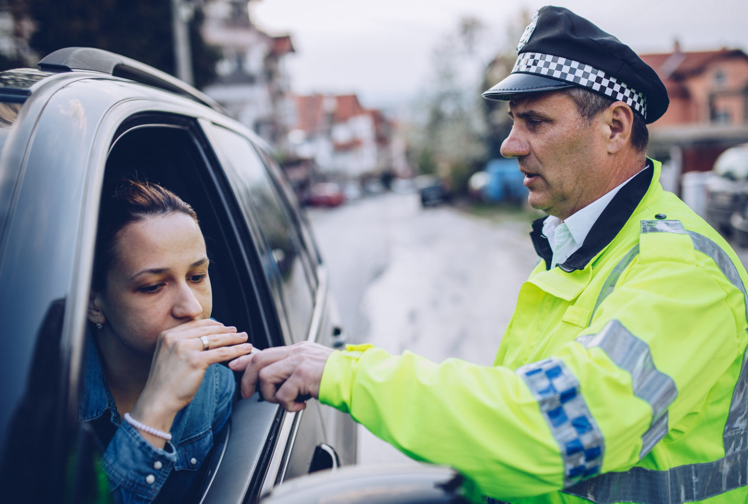 Police officer giving woman a breath test to check for drink driving.